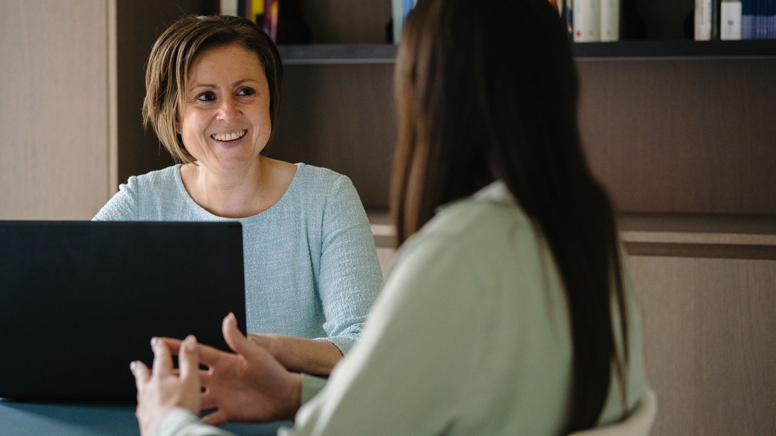 Advocaat Tina Devlamynck in gesprek terwijl ze notities neemt op een laptop.